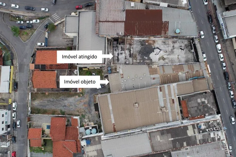 Vista aérea de quarteirão comercial com setas indicando o imóvel atingido pelo incêndio, sem cobertura, e o imóvel objeto da perícia, colado a ele